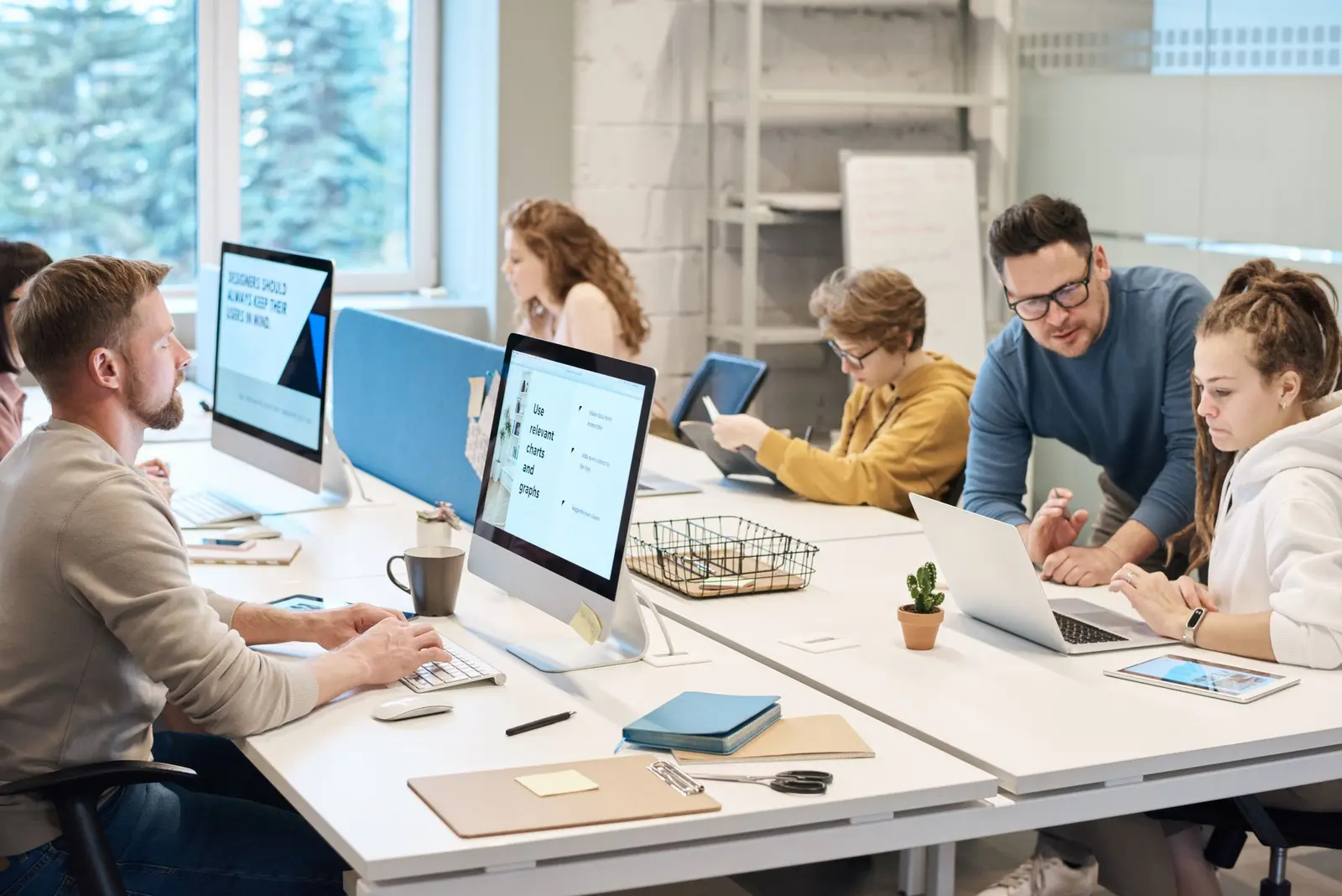 People working at desktop computers in a bright open-plan office