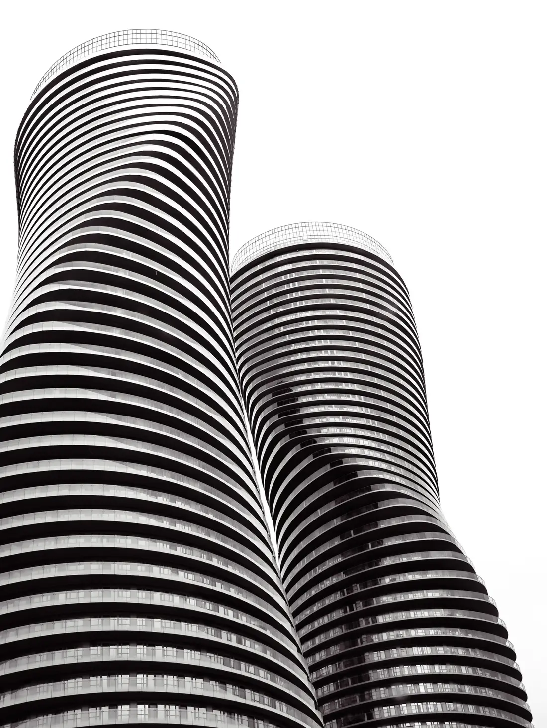 The curving Absolute World residential towers in Mississauga, Ontario, against a pale sky